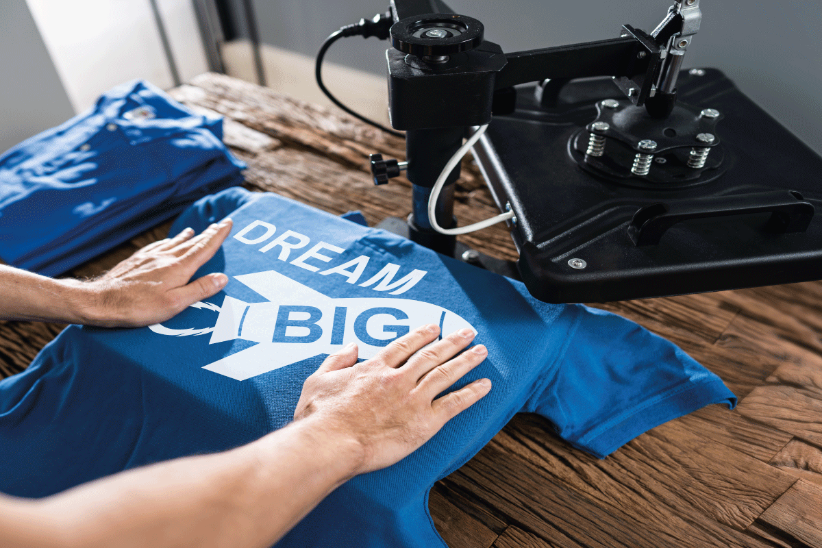 man heat pressing a quote in white DTF ink onto a blue polo shirt using the DTF printing method, illustrating the outstanding results and efficiency of this textile printing technique.